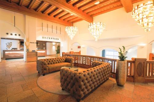 eine große Lobby mit Stühlen, einem Tisch und Kronleuchtern in der Unterkunft Best Western Premier Bayerischer Hof Miesbach in Miesbach