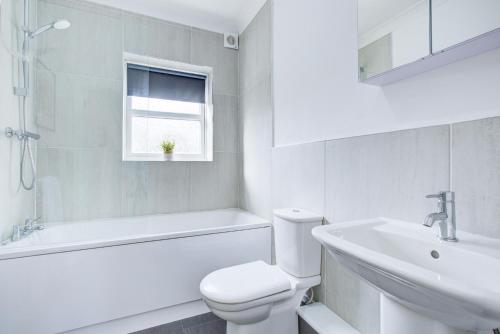 a white bathroom with a toilet and a sink at Stylish Two Bedroom Apartment With Free Parking! in Romford