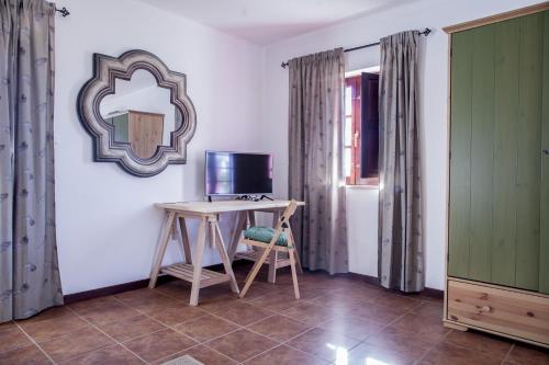 a room with a desk and a television and a mirror at Refúgio do Monte in Odemira
