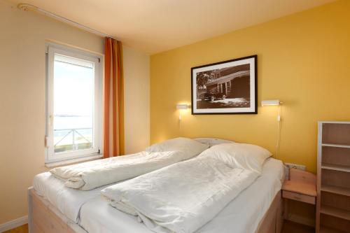 1 dormitorio con 1 cama con sábanas blancas y ventana en Strandhotel 14, en Laboe
