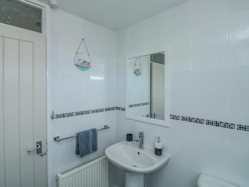 uma casa de banho branca com um lavatório e um espelho em Bay View em Paignton