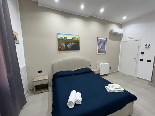 um quarto de hospital com uma cama com lençóis azuis e sapatos brancos em Room25mq em Cercola