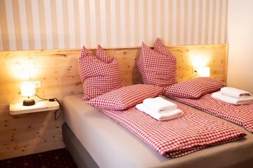 a bed with red and white checked sheets and pillows at Rösslgut Bed & Breakfast in Zederhaus