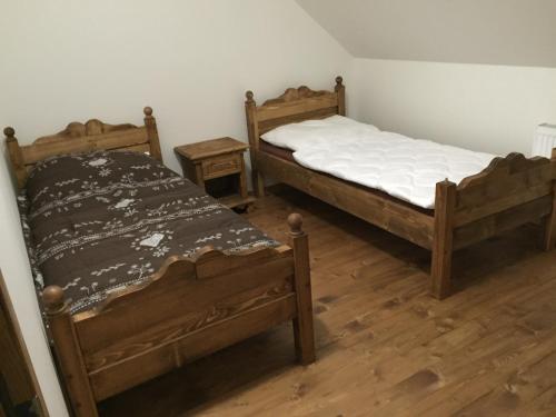 two twin beds in a room with wooden floors at Chata Vločka - Orava Snow v lyžiarskom stredisku in Oravská Lesná