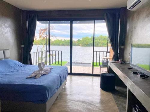 Schlafzimmer mit einem Bett und Blick auf das Wasser in der Unterkunft Kram Farmstay in Nakhon Pathom