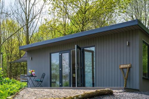 a small shed with glass doors and a patio at Lakeside Eco Lodge- 'Heron' in Bishampton
