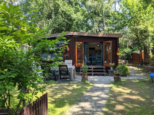 a small cabin with a table and chairs in a yard at Sfeervol chaletje in een rustige bosrijke omgeving in Diessen