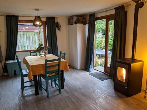 a dining room with a table and a wood stove at Sfeervol chaletje in een rustige bosrijke omgeving in Diessen