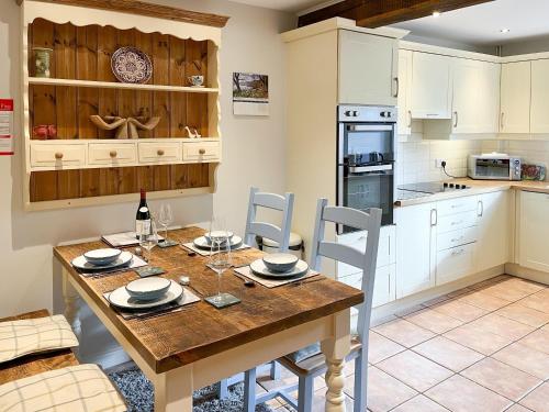 a kitchen with a wooden table with chairs and a dining room at Lavender Cottage in Stretton on Fosse
