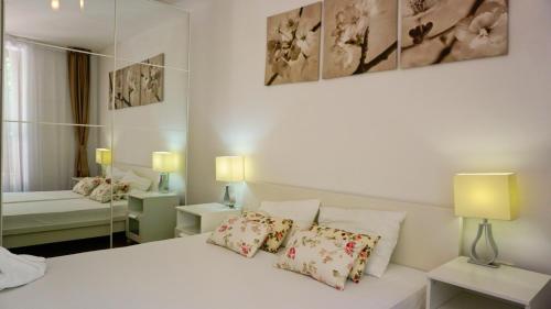 een slaapkamer met een wit bed met kussens en een spiegel bij Byala Cliff Sea View Penthouse in Byala