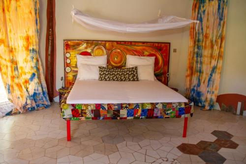 łóżko z kolorowym zagłówkiem w pokoju w obiekcie Mama Africa Art Residence & Art Center Gambia w mieście Tanji