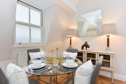 a dining room with a glass table and chairs at London Choice Apartments - South Kensington - Mews House II in London
