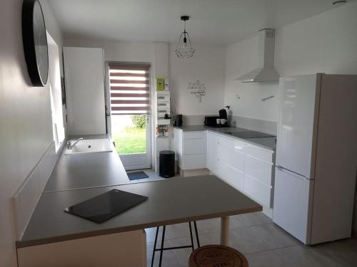 a white kitchen with a table and a refrigerator at Le Watt'else in Watten