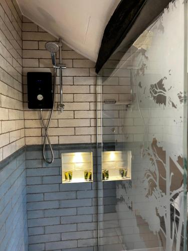a bathroom with a shower with lights on the wall at Elm Cottage in Northallerton