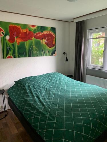 een groen bed in een slaapkamer met een schilderij aan de muur bij Ruim chalet op de Veluwe in Beekbergen op recreatiepark Topparken met vrije tuin en eigen parkeerplaats in Beekbergen