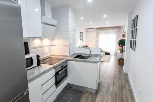 cocina blanca con fregadero y microondas en Apartamento renovado y confortable en el centro de Granada, en Granada