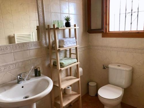 een badkamer met een wastafel, een toilet en een spiegel bij Casa El Boqueron:rust en relaxen met een prachtig uitzicht! in Cómpeta