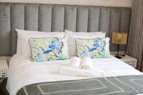 Elle comprend un grand lit avec des draps et des oreillers blancs. dans l'établissement Precious Paradise Zimbali Blvd, à Ballito