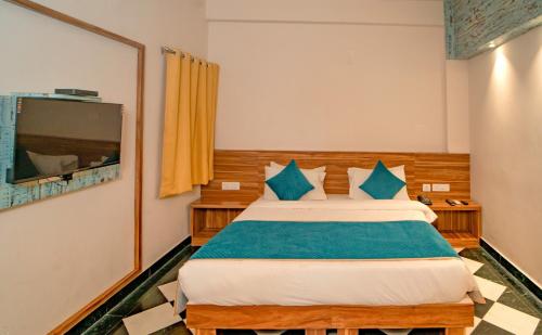 a bedroom with a bed with blue pillows and a tv at The Uddhav Elite in Udaipur