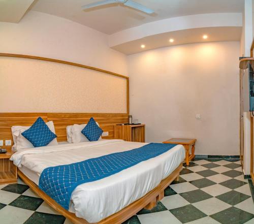 a bedroom with a large bed with blue pillows at The Uddhav Elite in Udaipur
