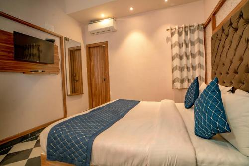 a bedroom with a large bed with blue and white pillows at The Uddhav Elite in Udaipur