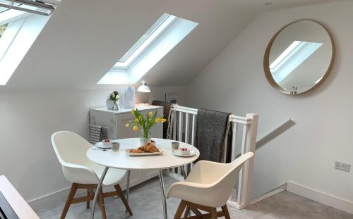 tavolo e sedie bianchi in una stanza con specchio di The Seawitch - harbourside apartment a Mousehole