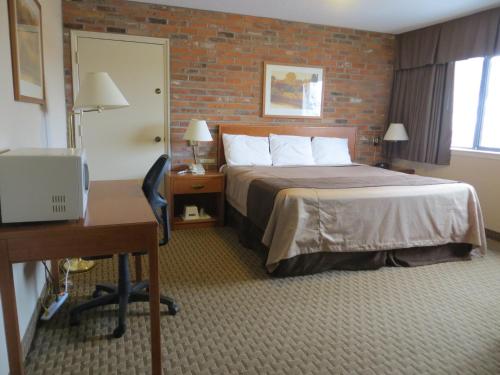 a hotel room with a bed and a desk at Travelodge by Wyndham Thunder Bay ON in Thunder Bay