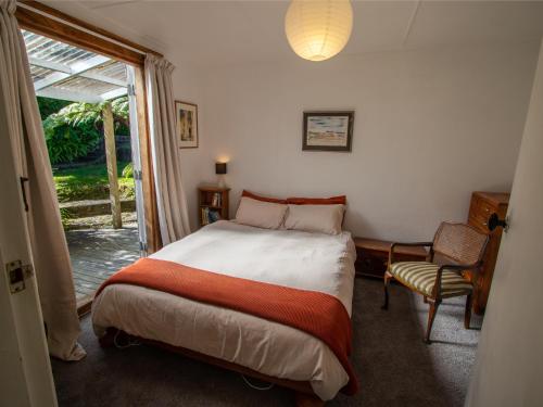 um quarto com uma cama e uma porta de vidro deslizante em Kereru Cottage - Pohara Holiday Home em Pohara
