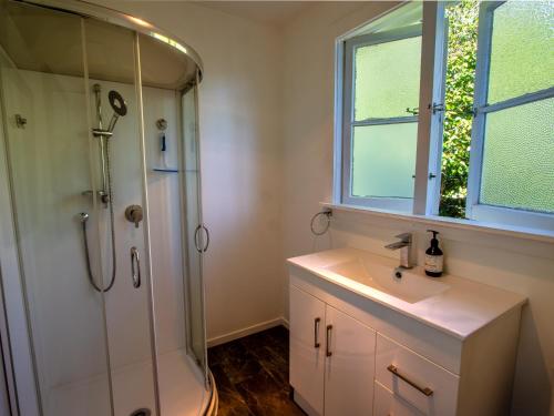 uma casa de banho com um chuveiro e um lavatório. em Kereru Cottage - Pohara Holiday Home em Pohara
