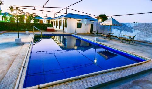 a swimming pool with blue water in front of a house at HARIYALI RESORT in Sardārgarh