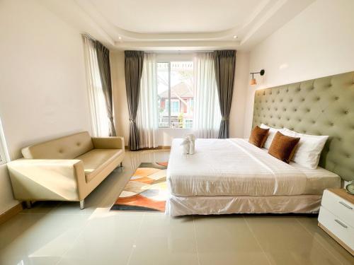 a bedroom with a large bed and a chair at Happy Land Residence in Ban Nam Cham