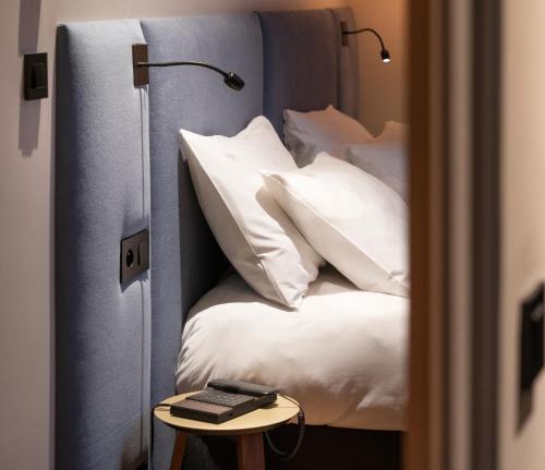 a bedroom with a bed with white pillows and a table at Hébé Hotel in Annecy