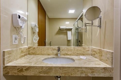 a bathroom with a sink with a mirror and a shower at Apart Hotel Centro de Brasília - Garvey Park Hotel in Brasilia