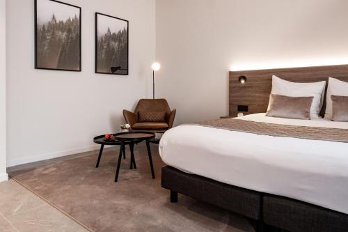 Cette chambre comprend un grand lit et une chaise. dans l'établissement Hotel Reynaert Bv, à Hulst