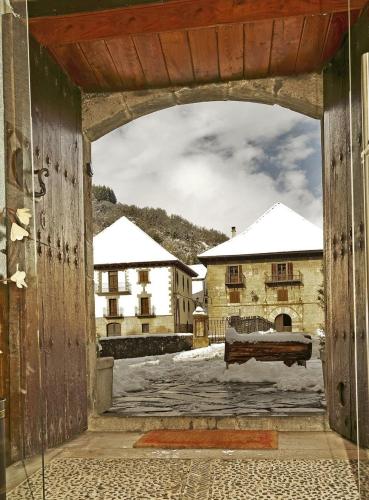 an open door to a courtyard with snow covered buildings at Hostal Orialde in Ochagavía