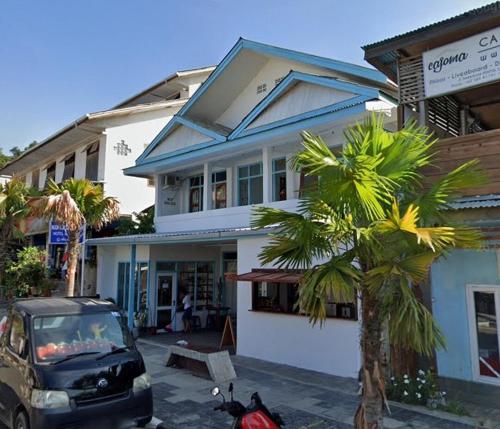 a car parked in front of a building with a palm tree at Komodo Indah Hotel in Labuan Bajo