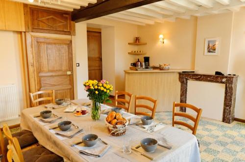 a dining room with a table with flowers on it at La Ferme aux Charmes in Solre-le-Château