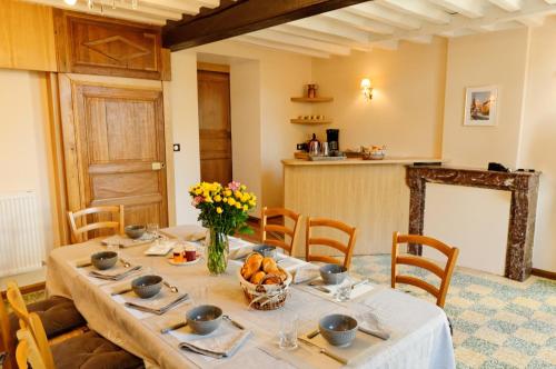 - une salle à manger avec une table et des fleurs dans l'établissement La Ferme aux Charmes, à Solre-le-Château