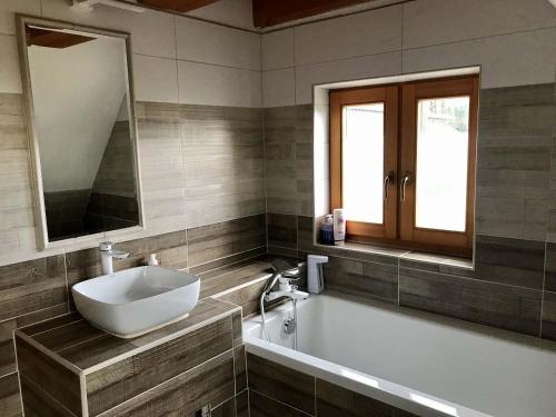 een badkamer met een wastafel en een bad met een spiegel bij Chalupa u kapličky Říčky v Orlických horách in Wüstenei