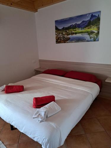 Una cama blanca con almohadas rojas encima. en El Malget, en Tuenno