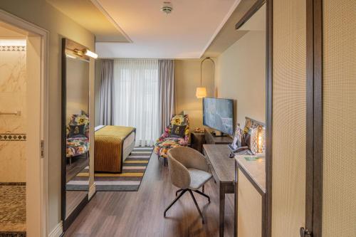 a hotel room with a desk and a bedroom at Hotel Erbprinz - Gourmet & Spa in Ettlingen