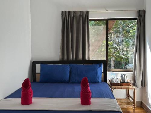 um quarto com uma cama azul e almofadas vermelhas em Happy Elephant Bungalows em Koh Rong Island