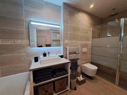 ein Badezimmer mit einem Waschbecken, einem WC und einem Spiegel in der Unterkunft Villa des Thermes, St Jean d'Angély in Saint-Jean-dʼAngély