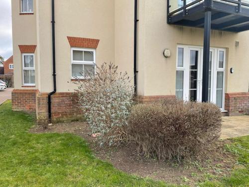 uma casa com um arbusto à frente em 2 Bedroom Ground Floor Flat em Haddenham