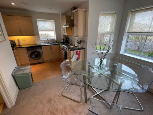 une cuisine avec une table en verre et deux chaises dans l'établissement 2 Bedroom Ground Floor Flat, à Haddenham