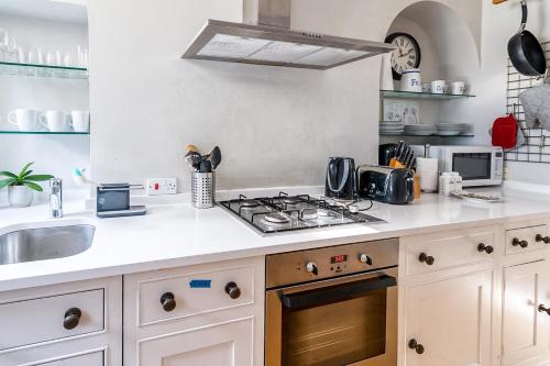 a kitchen with a stove top oven next to a sink at Cozy and Spacious Kensington Maisonette in London