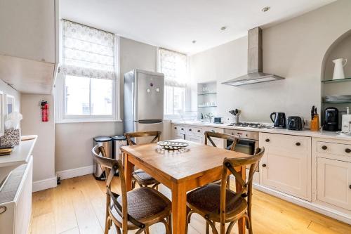 a kitchen with a wooden table and chairs at Cozy and Spacious Kensington Maisonette in London