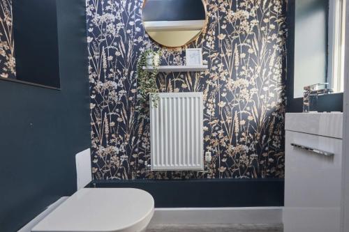 a bathroom with a white toilet and a blue wall at Homebird Property - The Willows in Leeds