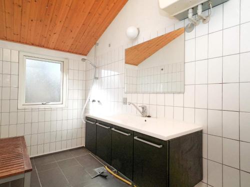 W wyłożonej białymi kafelkami łazience znajduje się umywalka i okno. w obiekcie Holiday home Rørvig XVI w mieście Rørvig