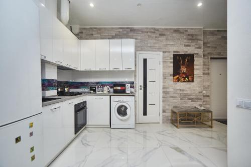 a kitchen with white appliances and a brick wall at Apartments Club Marine in Odesa